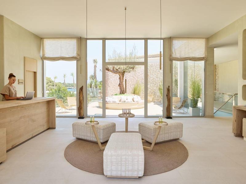 Jasny pokój hotelowy z dużymi oknami, nowoczesnymi meblami i widokiem na taras.