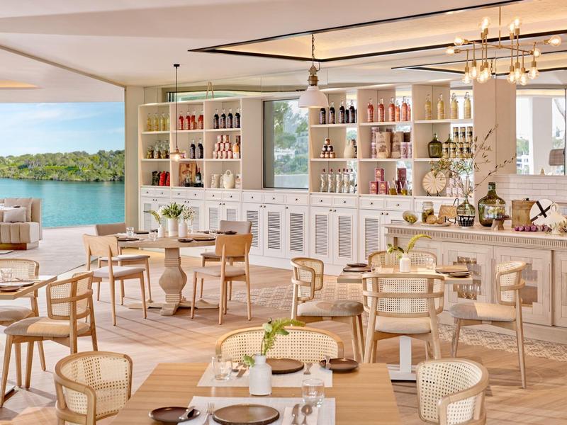 Jasno urządzone restauracja z drewnianymi krzesłami i widokiem na wodę oraz zieloną wyspę.