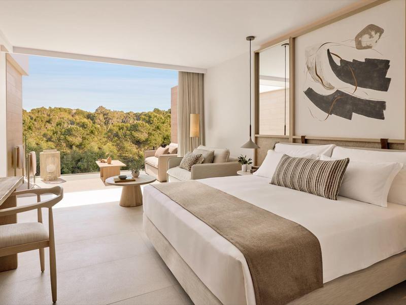 Nowoczesny pokój hotelowy z dużym łóżkiem i widokiem na zielony krajobraz i morze