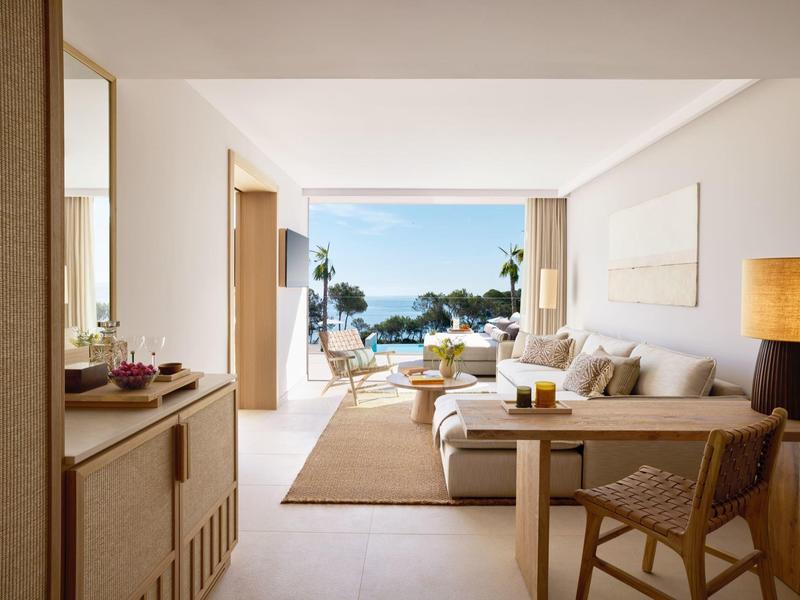 Jasny salon z otwartym widokiem na taras, basen i morze pod czystym niebem.