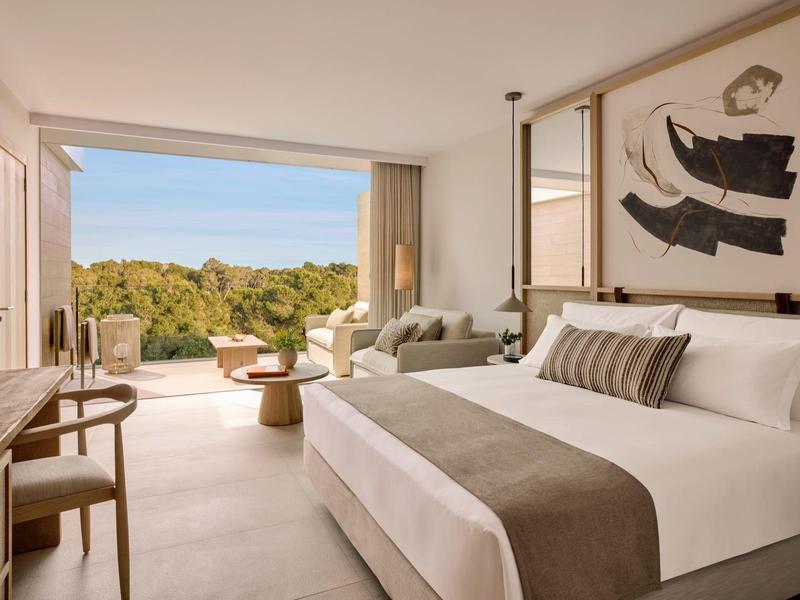 Nowoczesny pokój hotelowy z łóżkiem podwójnym i widokiem na taras oraz zielony krajobraz.