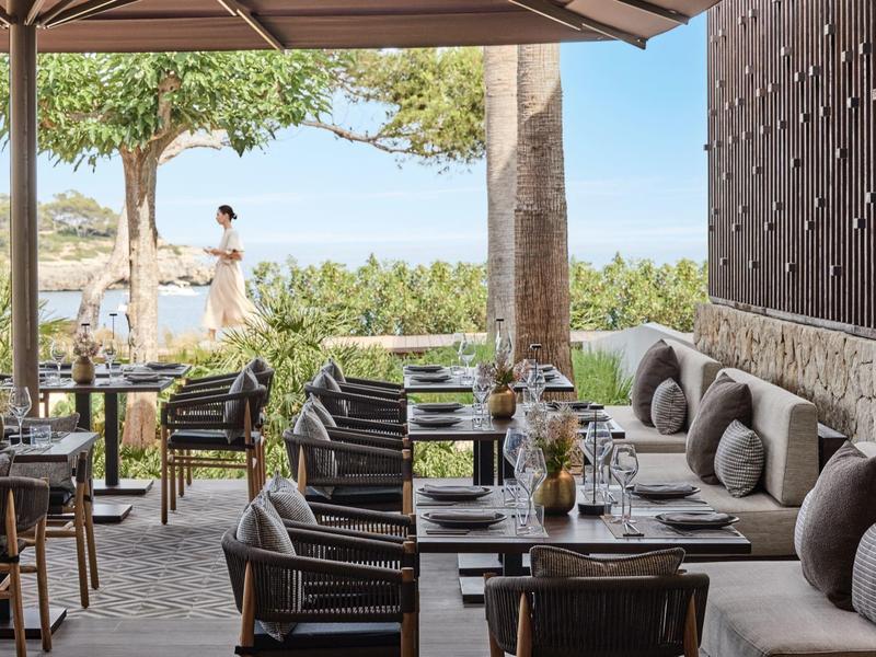 Przytulny taras z krzesłami, stołami i widokiem na przyrodę pod czystym niebem.