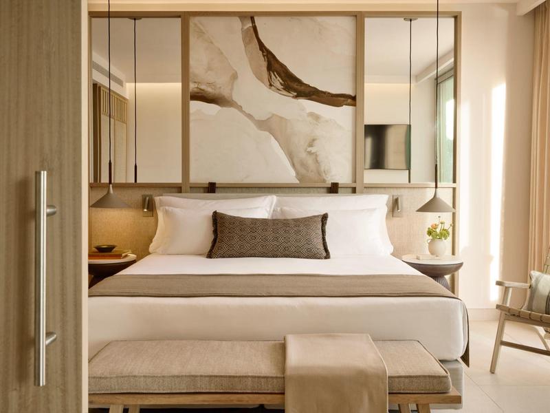 Elegancki pokój hotelowy z dużym łóżkiem, nowoczesną sztuką i miękkim oświetleniem.