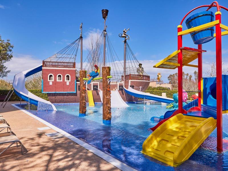 Colorful water playground with slide and boat-themed area under blue sky.