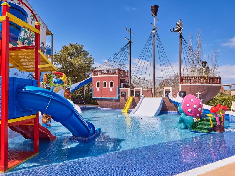 Colorful water playground with slides and play equipment in a hotel pool on a sunny day.