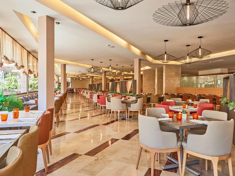 Modern hotel restaurant with comfortable chairs and warm daylight.