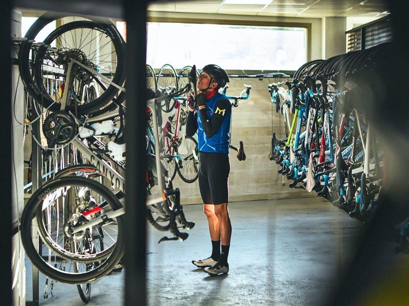 A man in sportswear selects a bike in a bright, well-organized bike storage room.