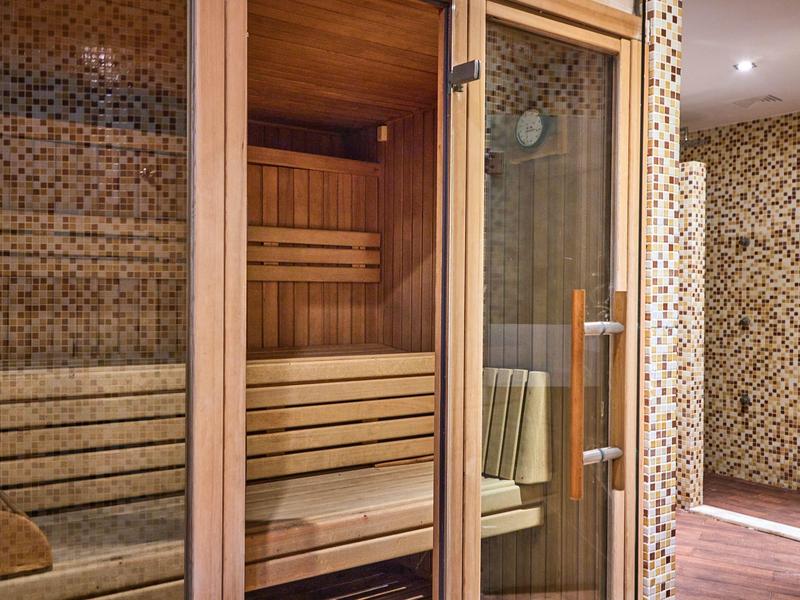 Interior view of a modern sauna with wooden benches and glass door in a wellness area.