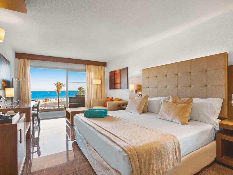 Chambre d'hôtel moderne avec grand lit et vue sur la mer par des portes coulissantes en verre