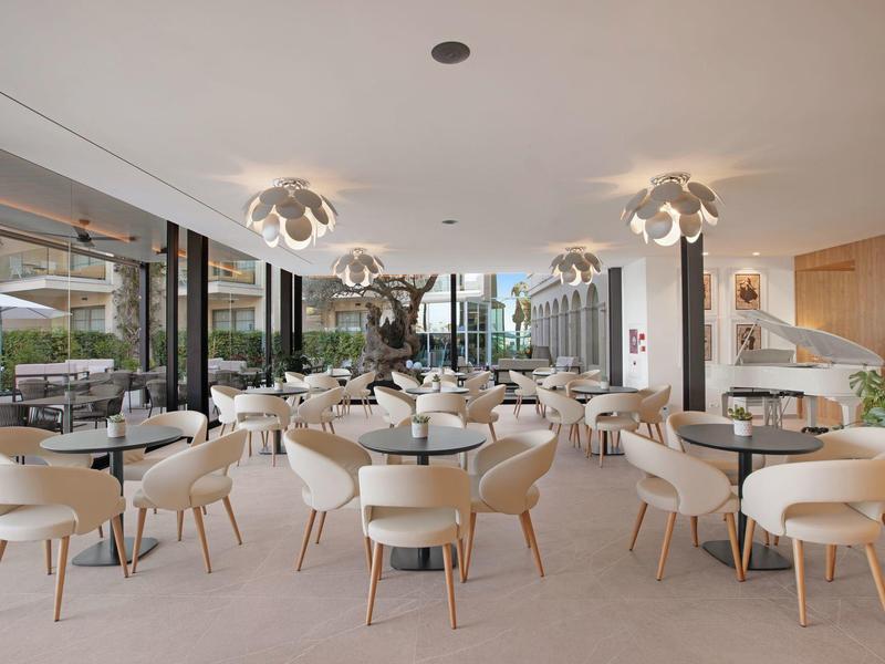 Restaurant moderne et lumineux avec chaises blanches et tables rondes dans un hôtel.