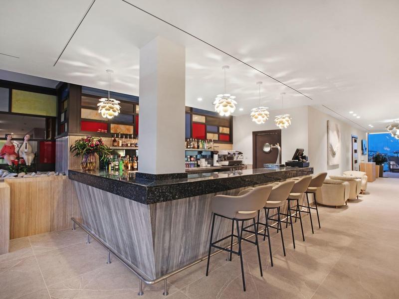 Espace bar d'hôtel moderne avec tabourets en bois et design lumineux et aéré.