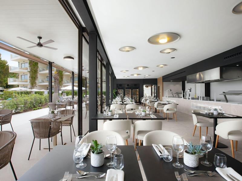 Restaurant moderne avec façade en verre et terrasse extérieure, tables et chaises élégantes.