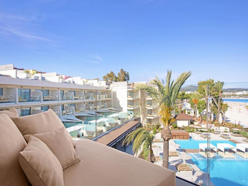 Vue d'une terrasse avec canapé sur la piscine et la mer par temps ensoleillé.