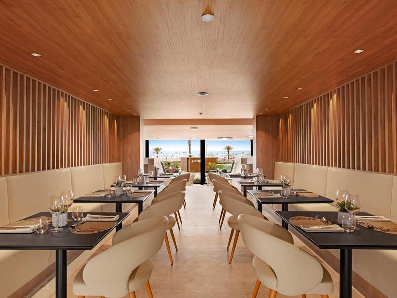 Restaurant moderne avec murs en bois, tables noires et chaises blanches.