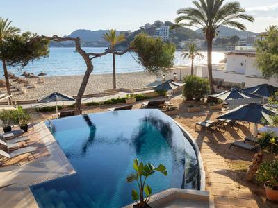 Piscine extérieure avec transats et palmiers au bord de la plage de sable et de la mer.