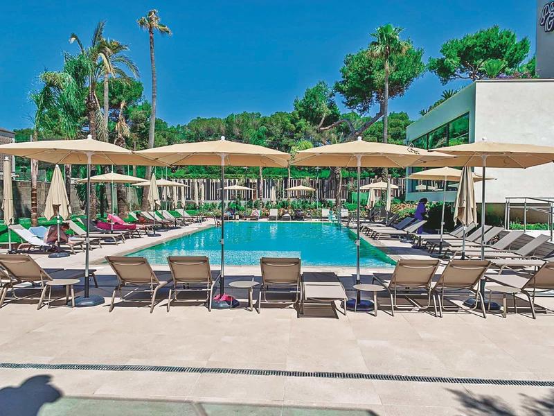 Jasná oblast u bazénu s lehátky a slunečníky pod modrou oblohou