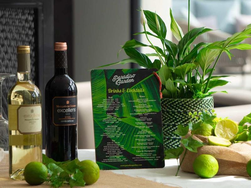 Lahve vína, čerstvé ingredience a květina v květináči na stole v moderní místnosti.