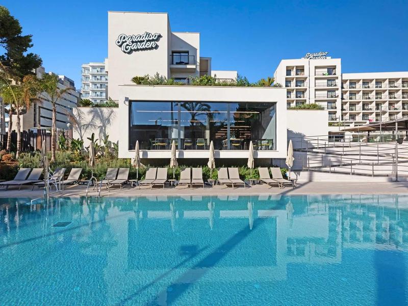 Moderní hotelový komplex s velkým bazénem a lehátky za slunečného dne.