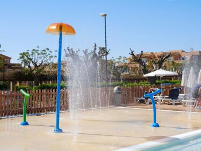 Plac zabaw wodnych z tryskającymi strumieniami wody i kolorowymi urządzeniami pod czystym niebem.