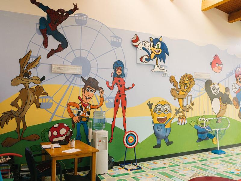 Kolorowa mural z postaciami z kreskówek w pokoju przyjaznym dzieciom z drewnianym sufitem.