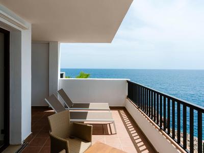 Balcón con tumbonas y vista al mar, muebles blancos modernos y barandilla