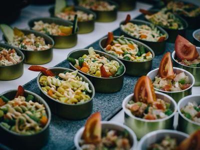 Mehrere Schalen mit gemischtem Nudelsalat und Gemüse, dekoriert mit Tomatenspalten und Salatblättern.