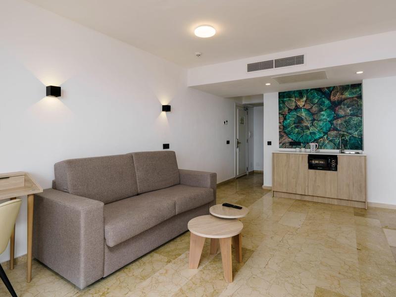 Sala de hotel moderna con sofá gris, mesas de centro de madera y decoración en la pared