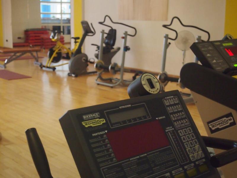 Salle de sport avec divers équipements d'exercice sur un sol en bois clair.