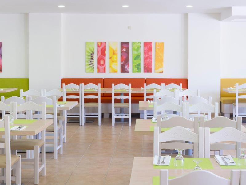 Salle à manger lumineuse et moderne avec des tableaux colorés et des chaises blanches.