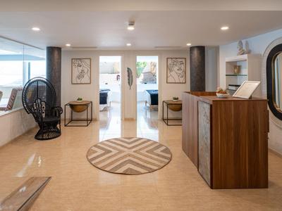 Modern hotel reception with wooden counter, round rug, and seating beside large windows.