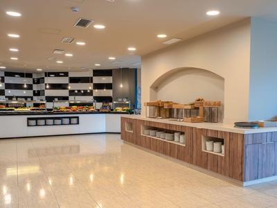 Bright hotel kitchen with wooden shelves and buffet area under warm lighting.