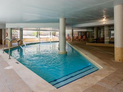 Indoor pool with rectangular blue water basin and built-in ladder.