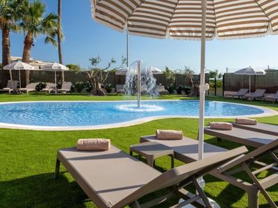 Espace piscine d'hôtel avec transats et parasols sous un ciel bleu clair