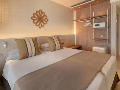 Chambre d'hôtel moderne avec lit double, literie beige et décoration murale.