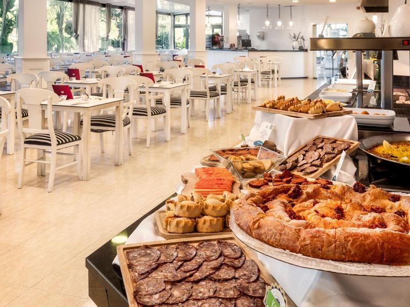 Jasna sala jadalna z stolikami i różnymi wypiekami na śniadanie.