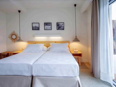 Camera d'hotel moderna con due letti singoli, comodini e grande finestra con tende.