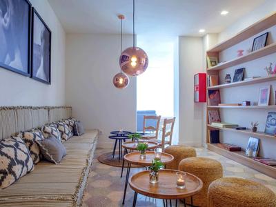 Gemütliches Wohnzimmer mit Sofa, Poufs, dekorativen Lampen und einem Bücherregal