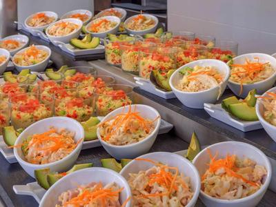 Buffet con varie insalate e piatti freschi in ciotole e bicchieri bianchi