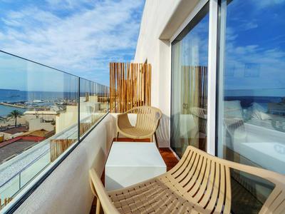 Balcone con parapetto in vetro, sedie e vista sul mare e sulla spiaggia.