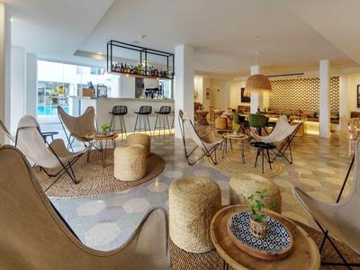 Lounge dell'hotel moderna e luminosa con poltrone accoglienti e tavoli dai toni caldi.