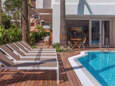 Area piscina moderna con lettini e decking in legno accanto a edificio bianco