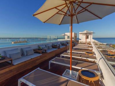 Terrazza panoramica con lettini, ombrelloni e posti a sedere con vista sul mare.