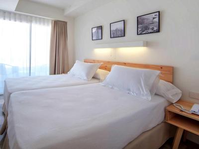 Camera d'hotel luminosa con due letti affiancati, mobili in legno e luce naturale.