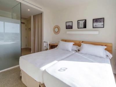 Camera luminosa con letto matrimoniale, testiera in legno e porte scorrevoli in vetro smerigliato.