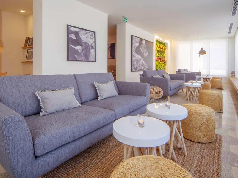 Soggiorno moderno con divani grigi, cuscini accoglienti e tavoli rotondi in un ambiente luminoso.