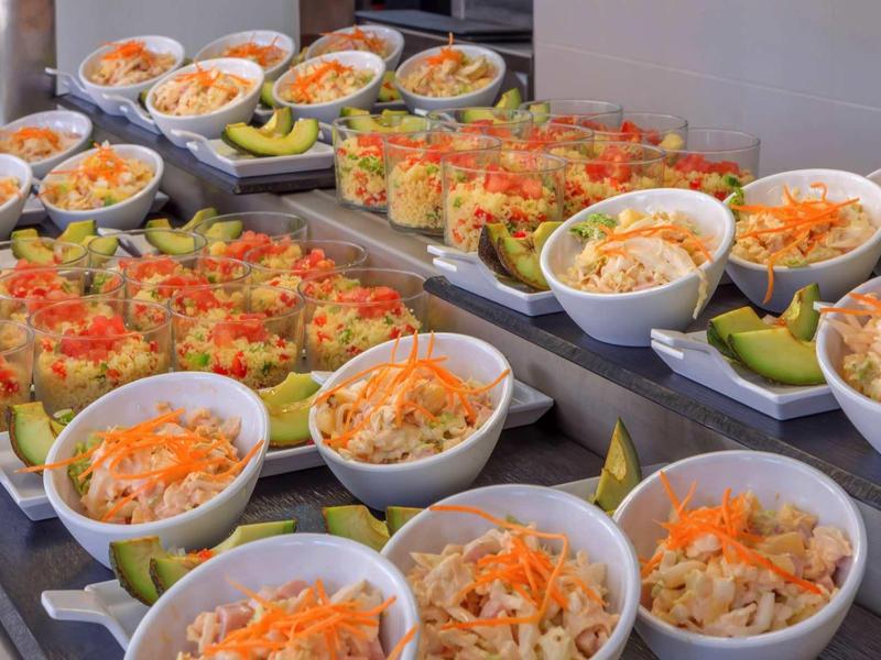 Buffet con varie insalate e piatti freschi in ciotole e bicchieri bianchi