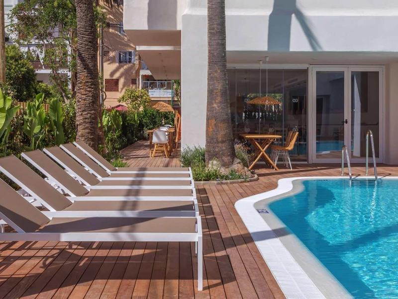 Area piscina moderna con lettini e decking in legno accanto a edificio bianco