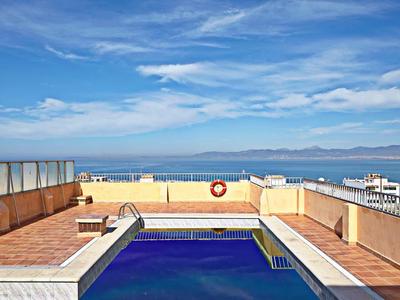 Piscina sul tetto con vista sul mare e cielo blu parzialmente nuvoloso.
