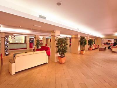 Ampia hall dell'hotel con sedute chiare e piante in vaso.