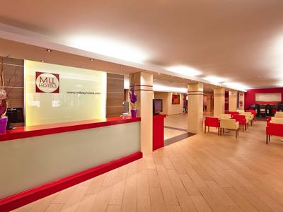 Reception d'hotel moderna con bancone rosso e sedie confortevoli.